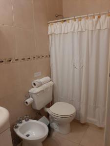 a bathroom with a toilet and a white shower curtain at Apart Boutique Flor de Lis - con cochera- in Santa Fe