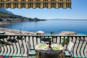 a table and chairs on a balcony with a view of the water at Apartments Waterfront IVAN 2 in Podgora