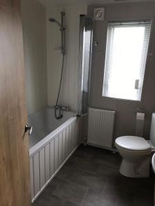 a bathroom with a bath tub and a toilet at 8 BIRTH LODGE ON CAYTON BAY HOLIDAY PARK in Scarborough