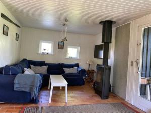 uma sala de estar com um sofá azul e um fogão a lenha em Sommerhus - Bratten strand em Jerup