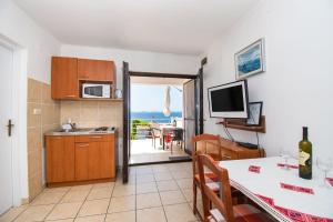 a kitchen and dining room with a table and a television at Apartments Danica in Murter