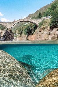 un puente sobre un cuerpo de agua junto a una montaña en Rusticus1706, en Lavertezzo