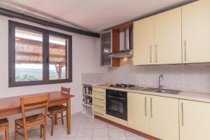une cuisine avec des placards blancs et une table en bois dans l'établissement Casa Porto Pollo, à Porto Pollo