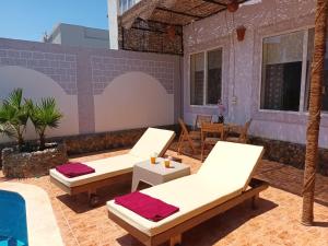 um pátio com 2 cadeiras e uma mesa em Rum i villa med pool em Hurghada