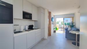 馬貝拉的住宿－OleHolidays 443 Romana Playa vistas al mar，一间带白色橱柜的厨房和一间客厅