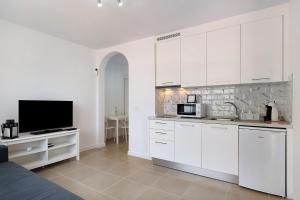 Una cocina con gabinetes blancos y un televisor de pantalla plana. en Noaian, en Puerto del Carmen