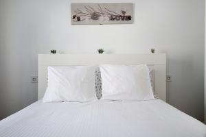 una cama blanca con sábanas y almohadas blancas en Noaian, en Puerto del Carmen 12 fotos más