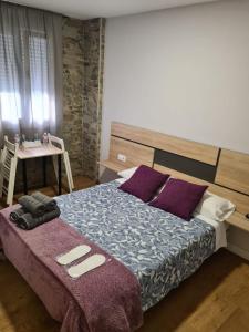 a bedroom with a large bed with purple pillows at Pensión Casa Douro in Santiago de Compostela