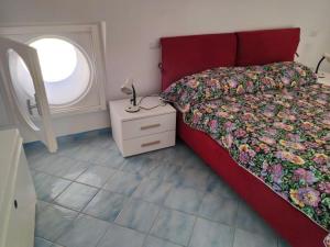 a bedroom with a red bed and a window at VisitPonza - La tana di Bacco in Ponza