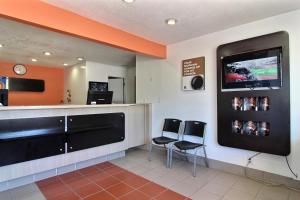 une salle d'attente avec deux chaises et une télévision à écran plat dans l'établissement Motel 6-Carlsbad, NM, à Carlsbad