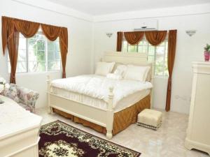 a white bedroom with a bed and two windows at Windmill Villa in Craighton