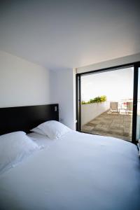 a bedroom with a bed and a view of a patio at Le Grand Hotel de la Plage in Biscarrosse-Plage