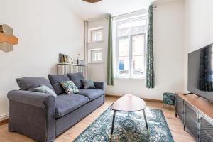 a living room with a couch and a tv at Le Grain de Sable in Thionville