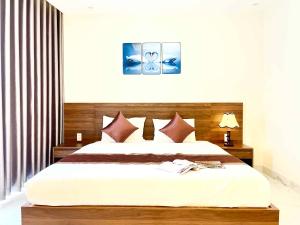 a bedroom with a large bed with a wooden headboard at Hoàng Triều Hotel - Marina Bình Dương in Thu Dau Mot