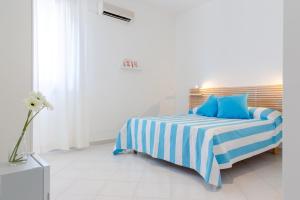 Un dormitorio con una cama azul y blanca con almohadas azules en Vidamarina - Camere al Mare, en Torre Lapillo