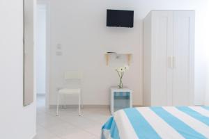 1 dormitorio con 1 cama y TV en la pared en Vidamarina - Camere al Mare, en Torre Lapillo