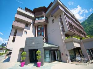 een wit gebouw met potplanten ervoor bij Hotel Le Morgane in Chamonix-Mont-Blanc