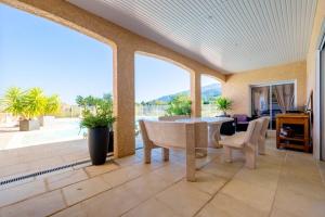 een woonkamer met een tafel en stoelen en een groot raam bij Maison de 2 chambres avec piscine privee terrasse amenagee et wifi a Montesquieu des Alberes in Montesquieu