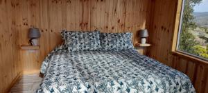 1 dormitorio con 1 cama en una pared de madera en Cabaña La Puntilla, en Vichuquén