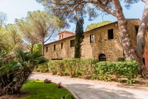 an exterior view of a stone house with trees at Villa Bolgherello in Marina di Bibbona