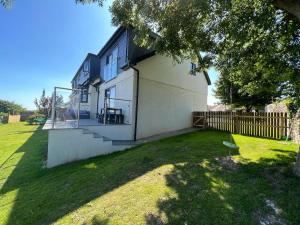 a white house with a fence and a yard at Orchard Lodge -Coastal Retreat, new build, village views, private garden and terrace in Saint Brides Major