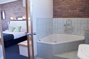 天鹅山Travellers Rest Motor Inn Swan Hill的客房内的浴室设有床和浴缸