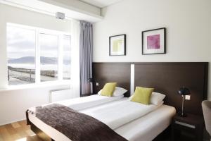 two beds in a hotel room with a window at Fosshotel Westfjords in Patreksfjörður