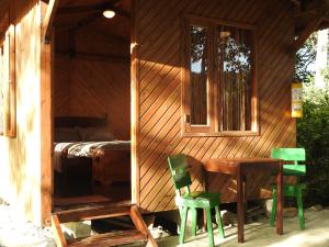 Cabaña de madera con mesa y 2 sillas verdes en Zasqua Glamping, en El Cape