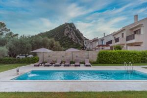 a swimming pool with chairs and a building at Villa Forte Mare in Petrovac na Moru