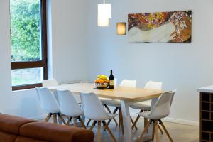 a dining room with a wooden table and white chairs at Villa Forte Mare in Petrovac na Moru