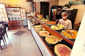 a person wearing a mask standing at a buffet at Pousada Solar de Geribá in Búzios