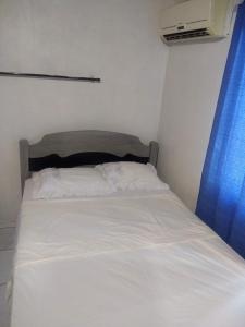 a bed with white sheets and a blue curtain at Casa Morumbi Foz do Iguaçu in Foz do Iguaçu