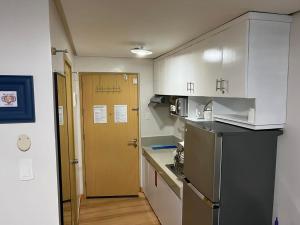 a small kitchen with a refrigerator and a door at XNY at SMDC Trees Residences Quezon City-Studio in Manila
