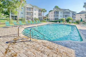 a large swimming pool with chairs and condos at Coastal Charm in Myrtle Beach