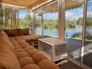 a living room with a couch and a view of a river at Muraszemenye Home in Muraszemenye