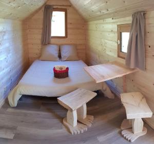 a bed in a wooden cabin with two benches at LE NOYER DU BARON in Le Lauzet-Ubaye