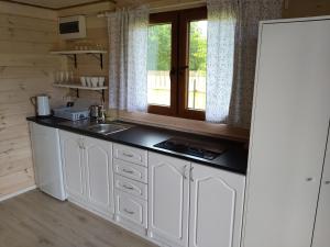 una cocina con armarios blancos y fregadero en Wielewski Zakątek, en Wiele