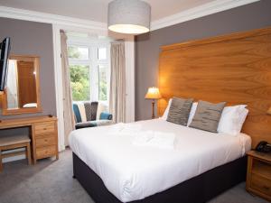 a bedroom with a large white bed and a window at Lyzzick Hall Hotel in Keswick