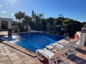 una piscina con 2 tumbonas junto a ella en Casa Bambu-ApartResort, en Vélez-Málaga