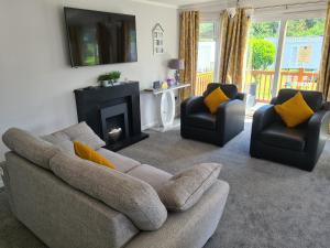 uma sala de estar com um sofá, 2 cadeiras e uma lareira em Mildreds Lodge with Hot Tub em Felton