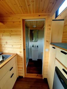 a small kitchen with a door leading into a bathroom at POP Tiny House Balaton in Káptalantóti
