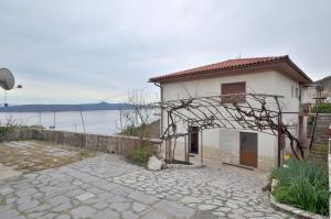 a house with a stone walkway next to a lake at Room Moscenice in Mošćenička Draga