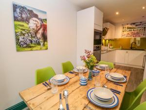 a dining room with a wooden table and green chairs at Herdwick Cottage in Brampton +19 photos