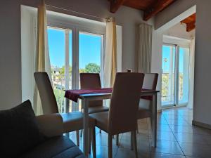 Un comedor con mesa y sillas y ventanas. en Da Cate - Appartamento al mare, en Grottammare