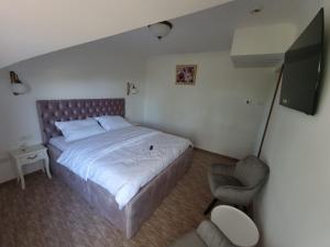 a bedroom with a large bed and a chair at Mini Paradis in Oradea