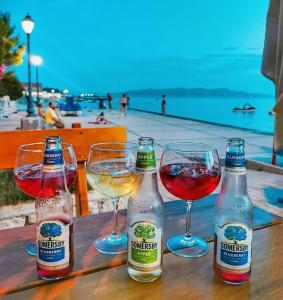 three bottles and two glasses of wine on a wooden table at Jasmina in Senj