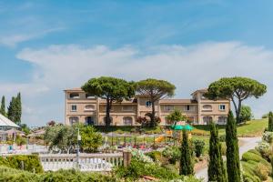 un grande edificio con alberi di fronte a un giardino di Borgo Felciaione a Riparbella