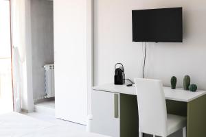 a white desk with a chair and a tv on a wall at Sofíta - Rooms & Apartment in SantʼAgata di Militello
