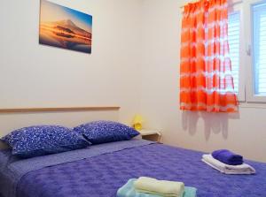 sypialnia z fioletowym łóżkiem i oknem w obiekcie Apartments Graciela w mieście Lastovo