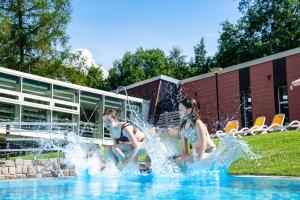 two girls playing in a fountain in a swimming pool at AHORN Waldhotel Altenberg in Kurort Altenberg